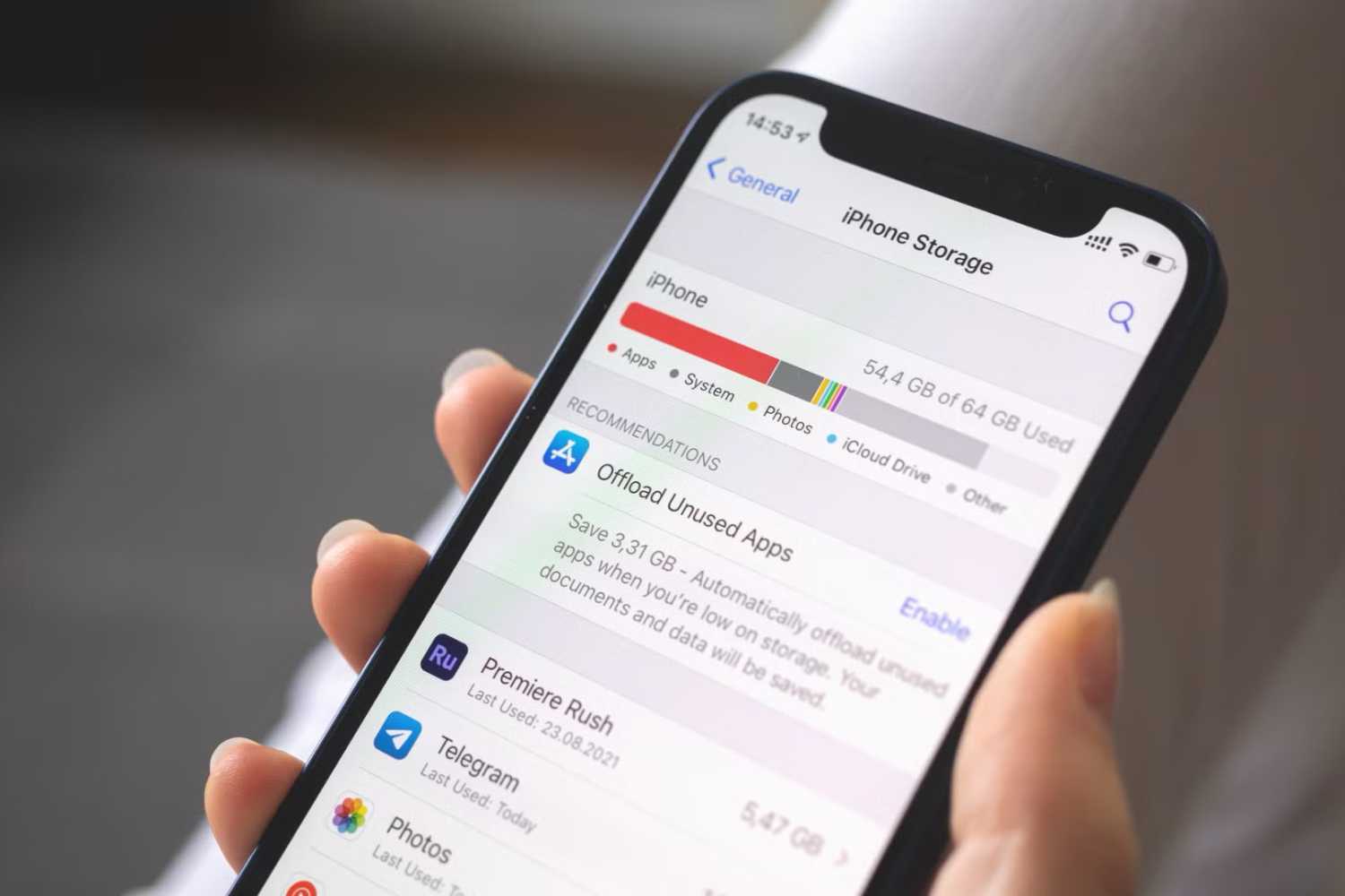 Apple iPhone is hand with blurred background showing device storage settings
